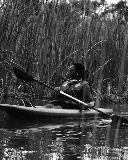 Dodoo paddling a kayak through tall reeds