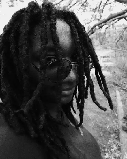 Close-up of Dodoo smiling through her locs