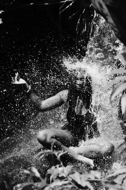 Dodoo sitting under a waterfall as it splashes over her